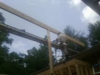Carpenter setting a ridge beam over a new addition frame — Ice Dam Removal by Roofing Brothers in Holtsville