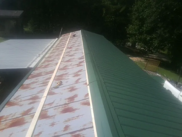 Old rusted panels beside newly installed green metal roofing — Wind Damage Roof Repair by Roofing Brothers in Holtsville