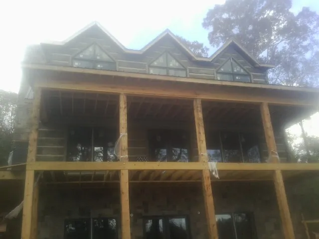 Dormers and porch framing on a large log home under construction — Roof Coating work by our crew in Holtsville