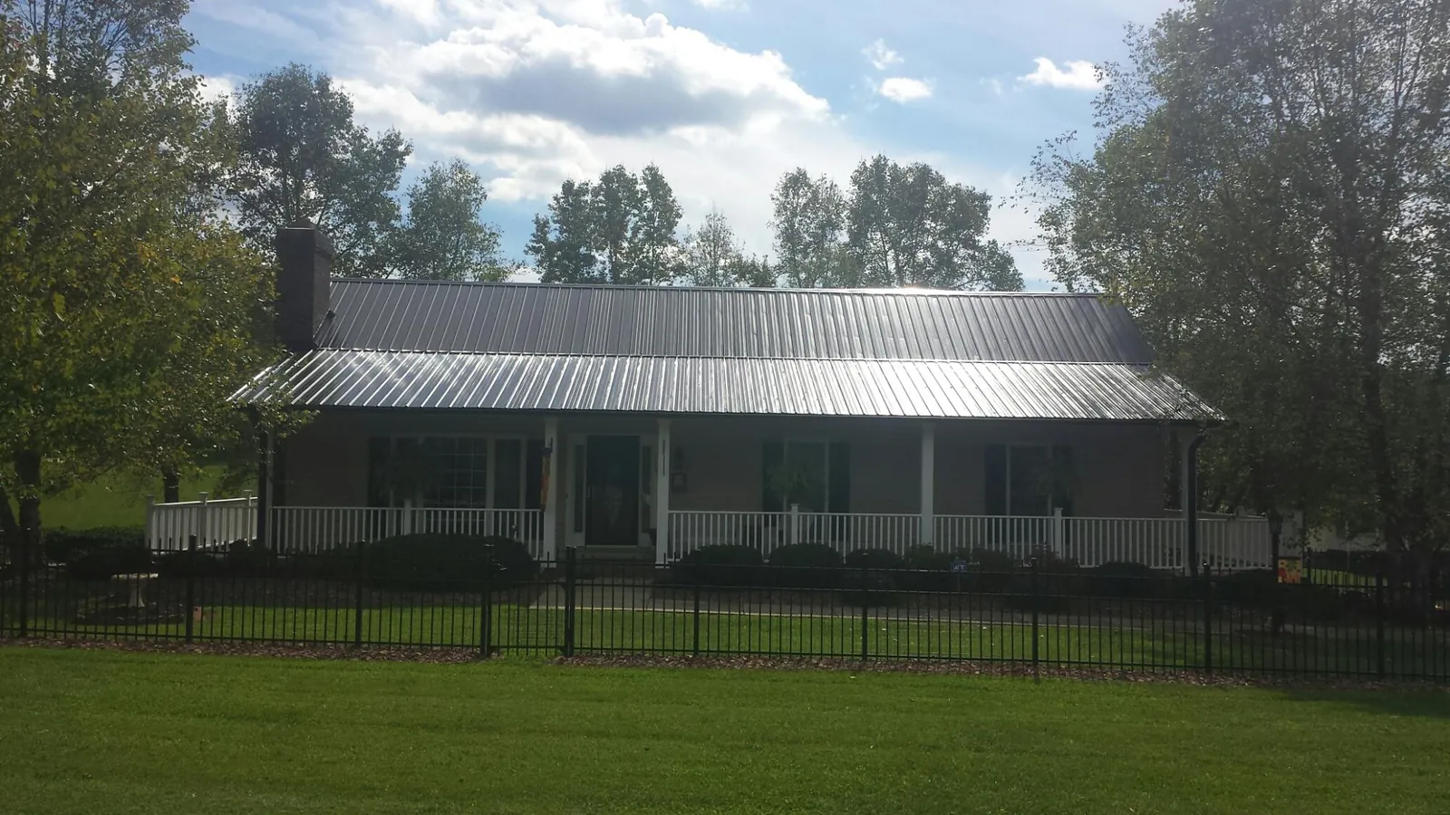 Gray metal roof on a brick ranch with a full width front porch — Gutter Guard Installation work by our crew in Holtsville