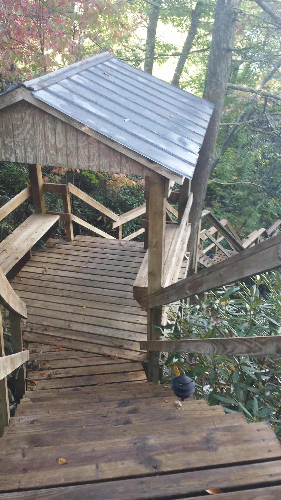Metal roofed shelter over wooden steps on a wooded walkway — Skylight Repair & Installation work by our crew in Holtsville