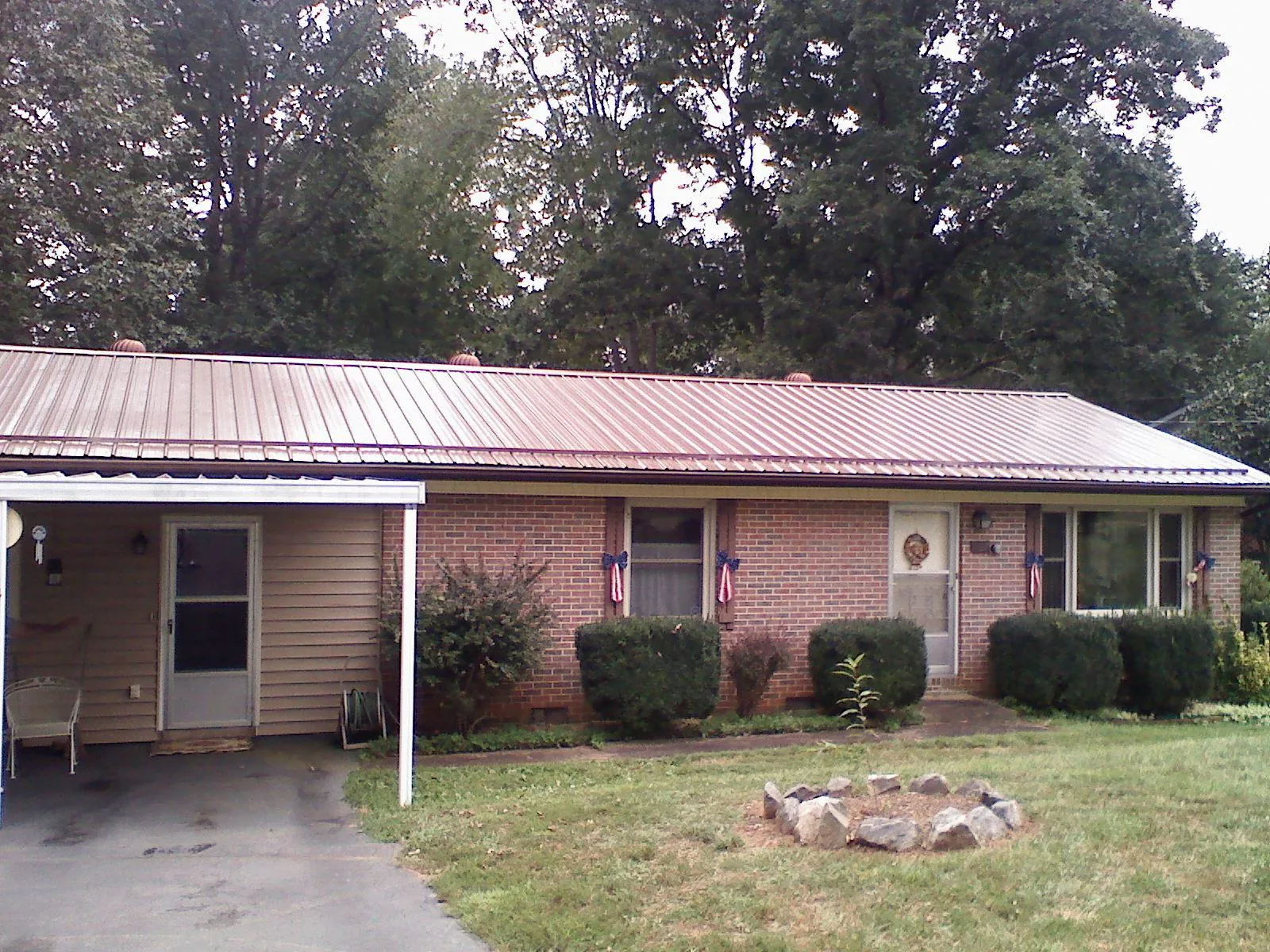 Bronze metal roof and carport on a brick ranch home — Roof Repair work by our crew in Holtsville